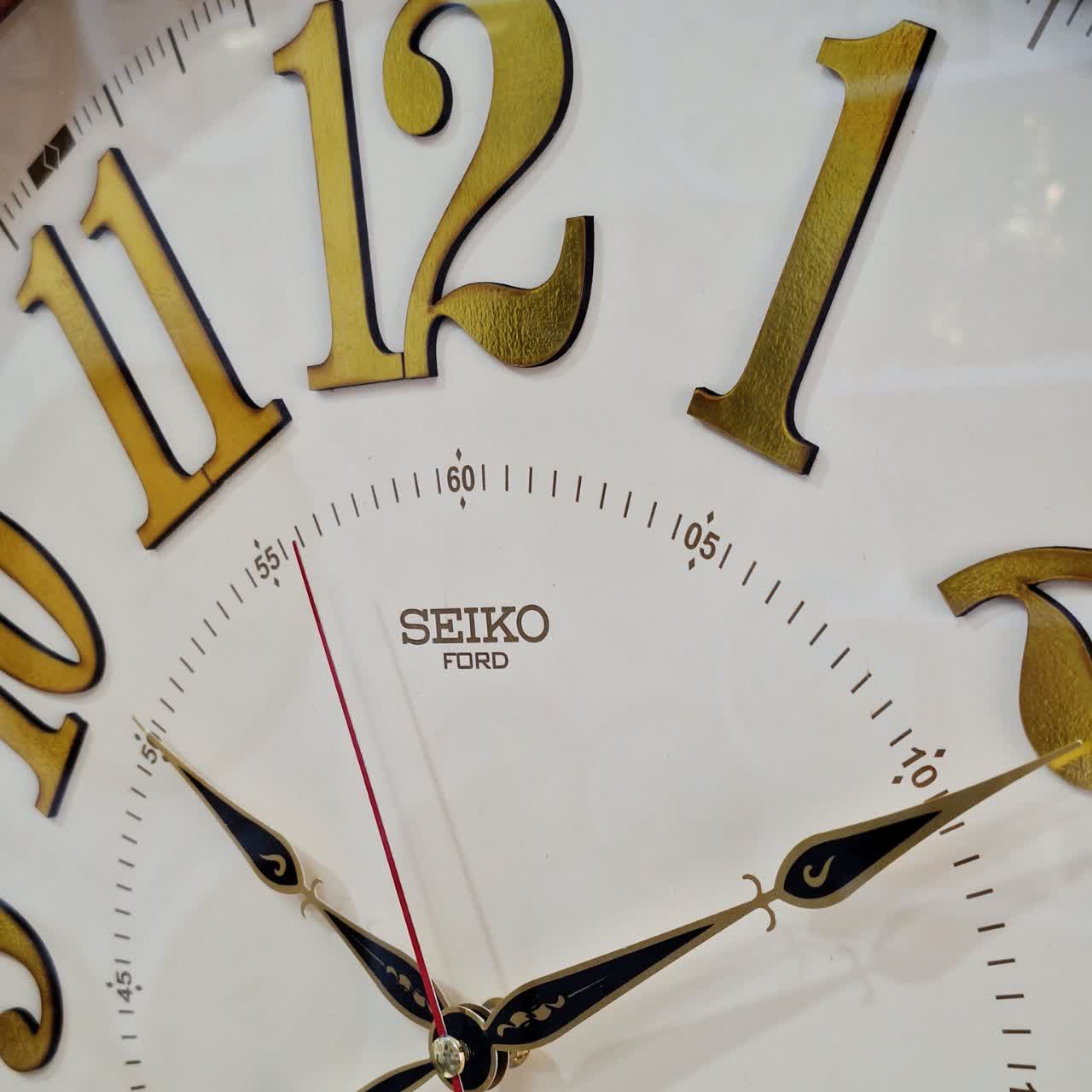 ساعت دیواری قهوه‌ای 60 سانتی‌متری چوبی از نمای نزدیک عقربه ها