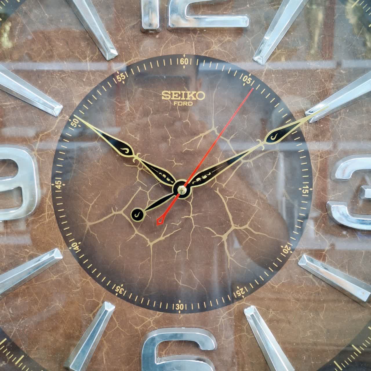 ساعت دیواری قهوه‌ای 60 سانتی‌متری چوبی از نمای نزدیک عقربه ها