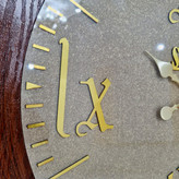 ساعت دیواری قهوهای 70 سانتیمتری چوبی با اعداد رومی طلایی نمای نزدیک اعداد دیگر