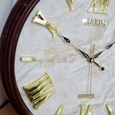 ساعت دیواری قهوهای 50 سانتیمتری فایبر داخل سفید با اعداد رومی طلایی از نمای نزدیک تر