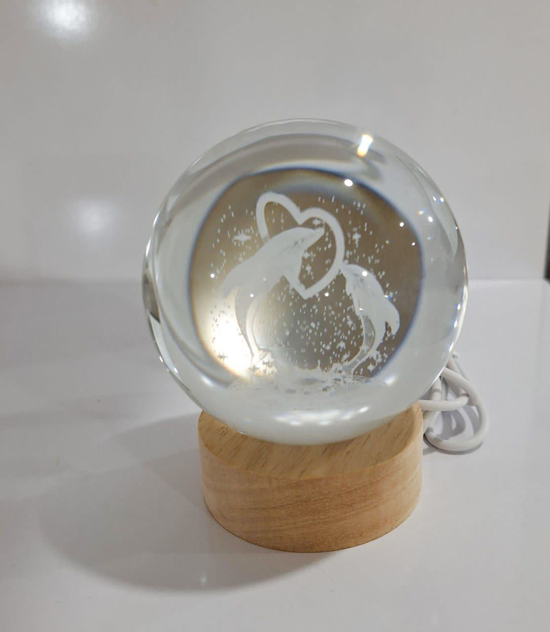 گوی شیشه‌ای شب‌تاب با دو دلفین عاشق روی پایه چوبی و نور LED ملایم