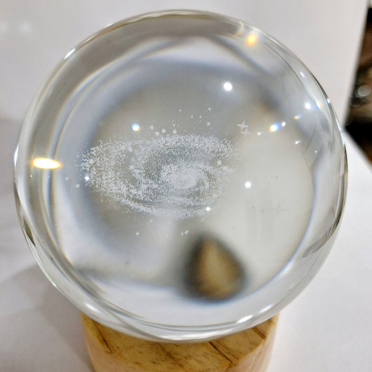 گوی شیشهای مدل کهکشان راه شیری با نور LED رنگی و پایه چوبی از نمای روز