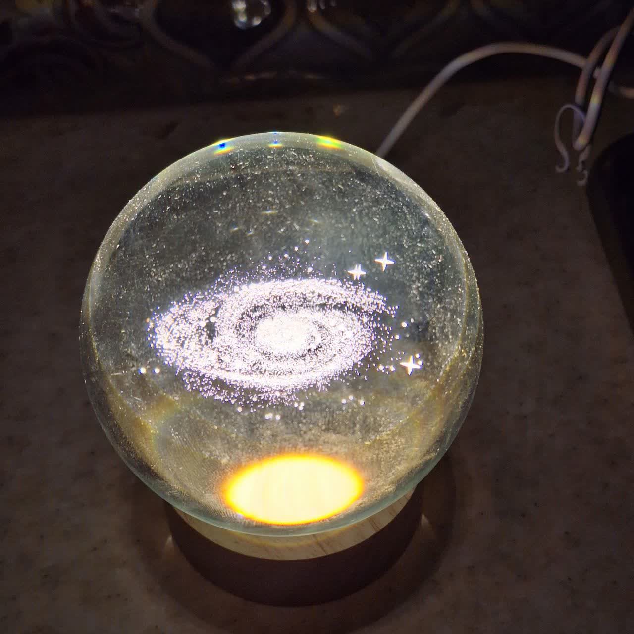 گوی شیشه‌ای مدل کهکشان راه شیری با نور LED رنگی و پایه چوبی