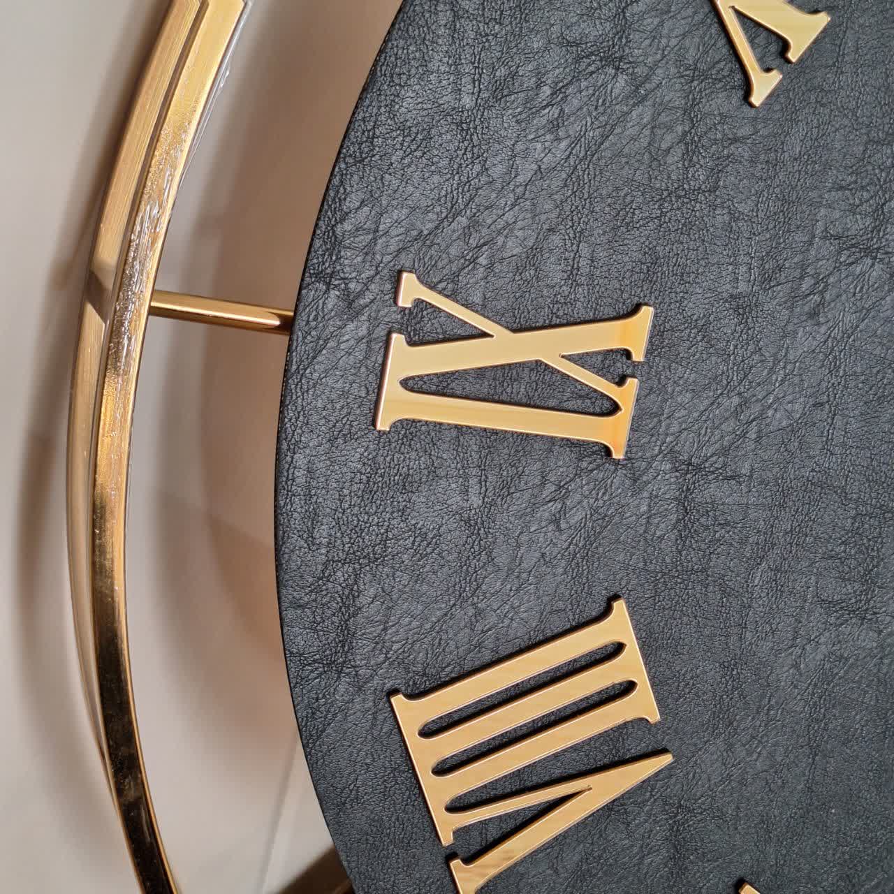 ساعت دیواری چرمی فلزی دو رینگ طلایی با صفحه چرم مشکی از نمای نزدیک تر