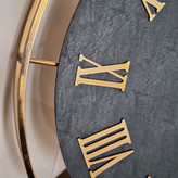 ساعت دیواری چرمی فلزی دو رینگ طلایی با صفحه چرم مشکی از نمای نزدیک تر