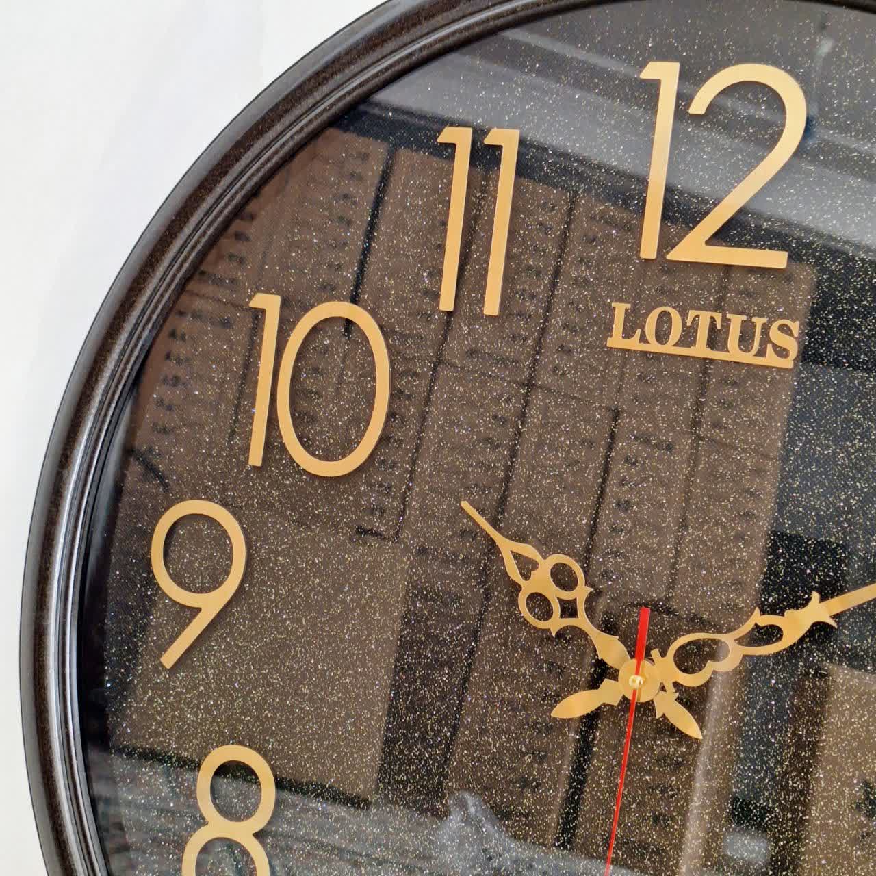 ساعت دیواری گرد ۶۵ سانتی لوتوس فایبر مشکی داخل اکلیلی با اعداد پلکسی بزرگ طلایی از نمای نزدیک تر