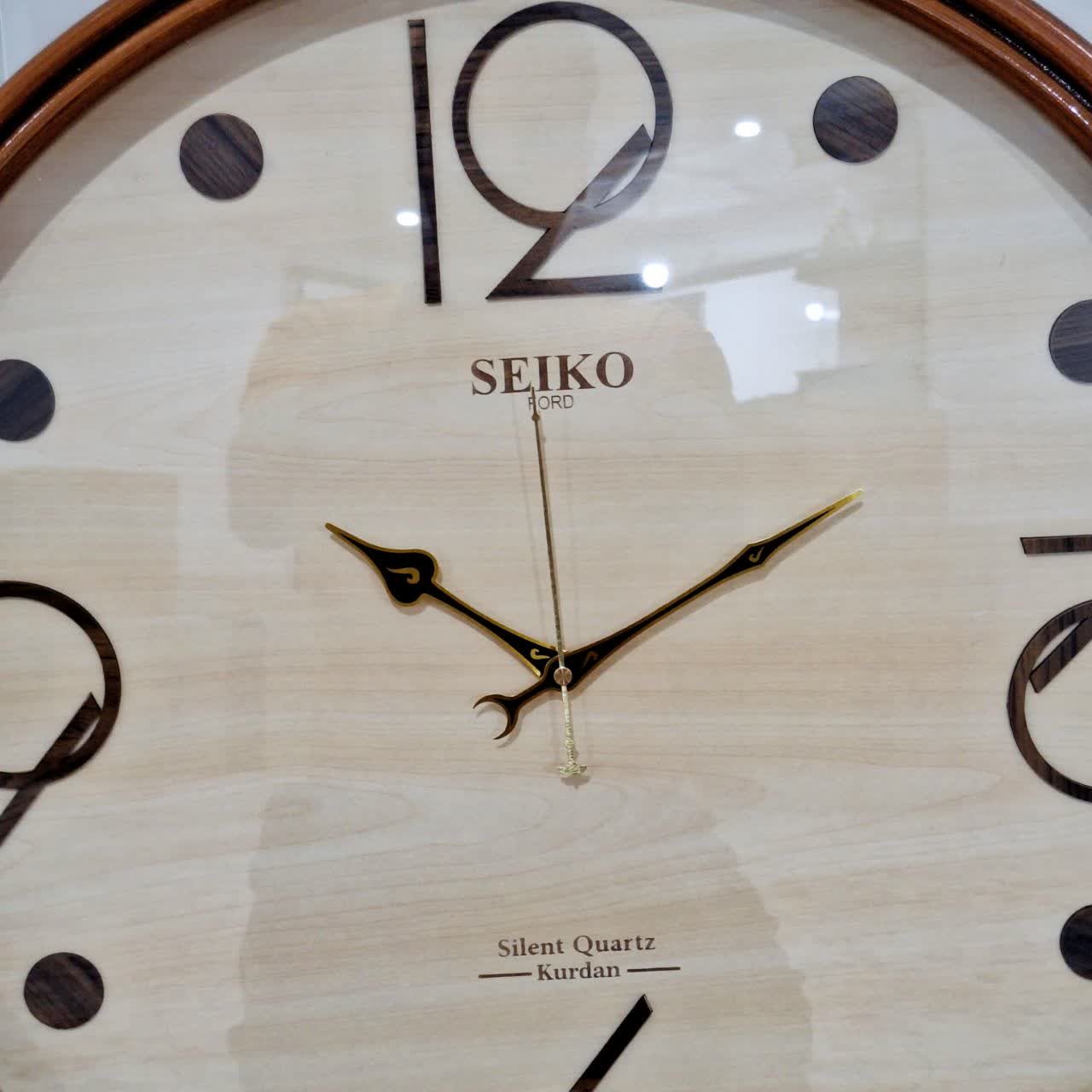 ساعت دیواری گرد ۶۰ سانتی چوبی قهوهای داخل کرم با اعداد فانتزی از نمای نزدیک